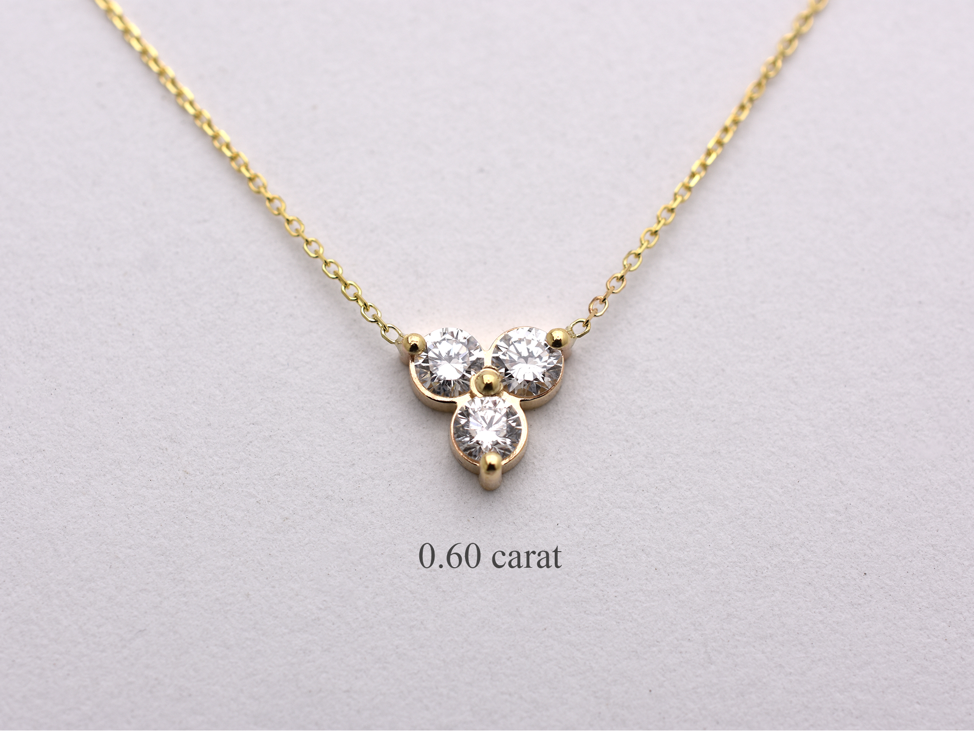 14k yellow gold necklace with a three-stone pendant of round brilliant cut 0.60  carat diamonds  on a white background