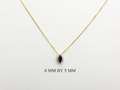  14K gold necklace featuring a marquise-cut sapphire center stone surrounded by a delicate diamond halo displayed on white background