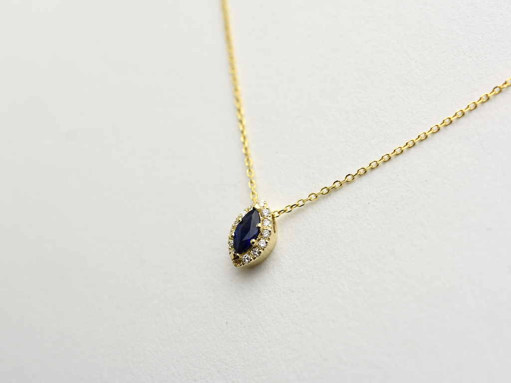  14K gold necklace featuring a marquise-cut sapphire center stone surrounded by a delicate diamond halo displayed on white background