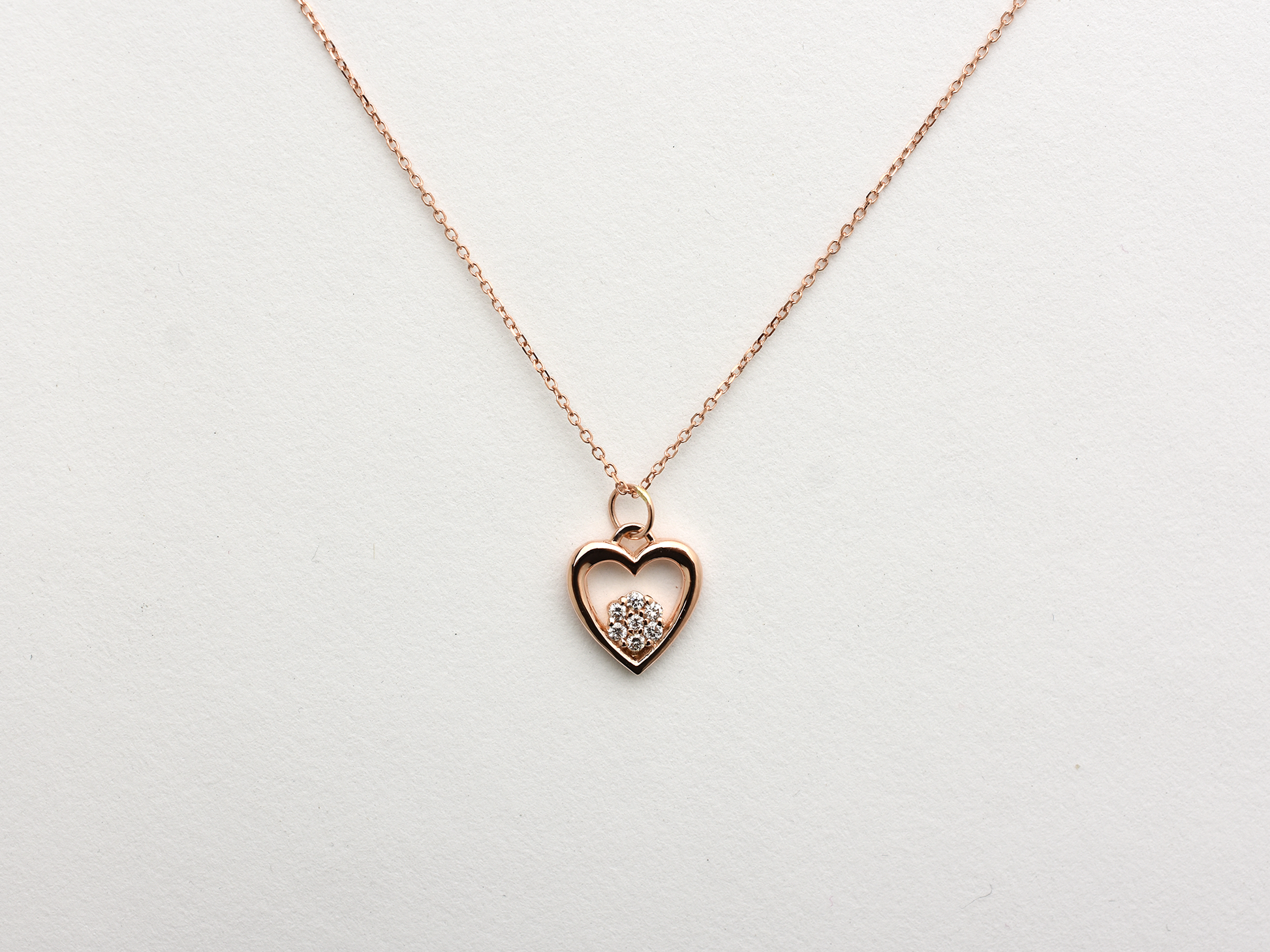 featuring a 14k gold heart necklace with a flower cluster motive 11 mm in dimension . the chain is a 14k sold gold cable link chain with a lobster lock 