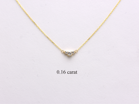  featuring a dainty three-stone diamond cluster pendant. The centerpiece consists of one slightly larger round brilliant cut stone flanked by two smaller stones in a minimalist prong setting on a fine gold cable chain with a lobster claw clasp