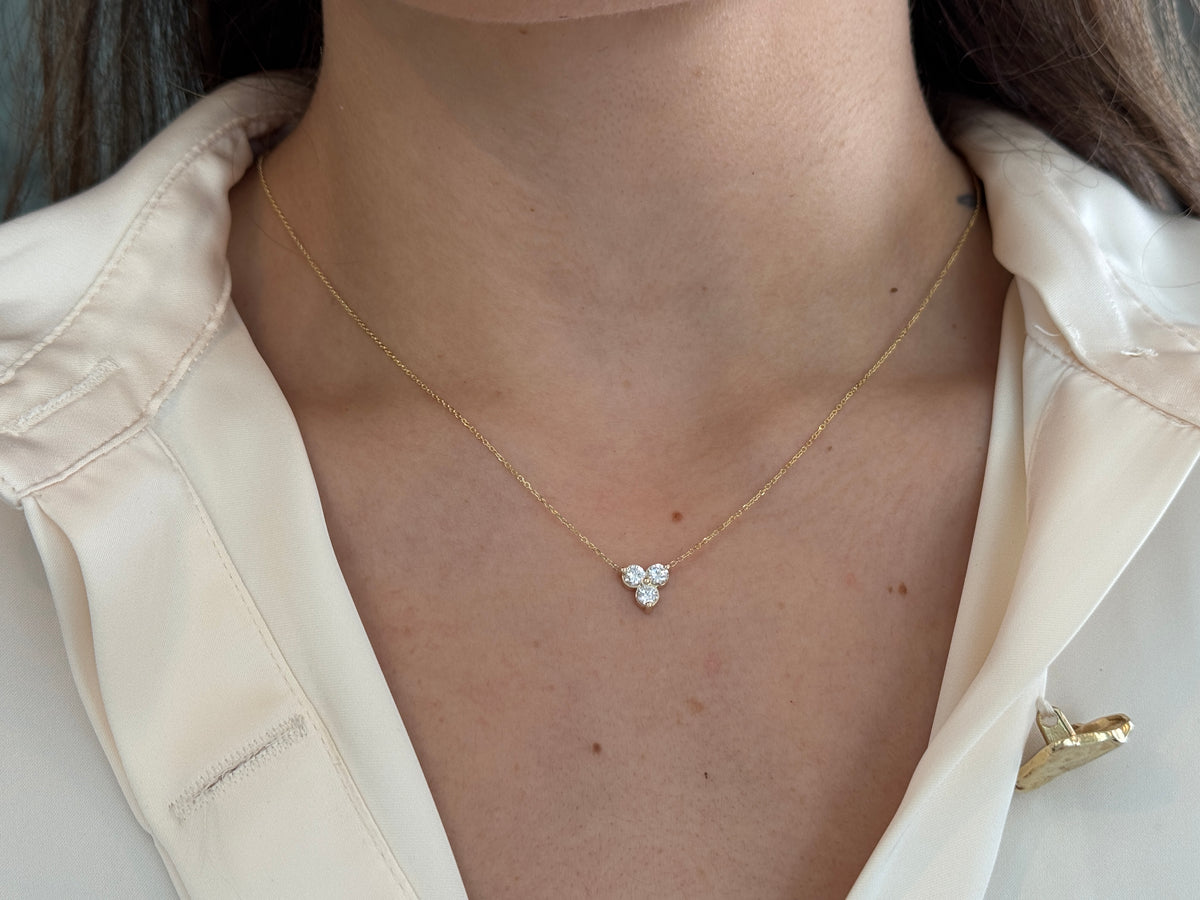 14k yellow gold necklace with a three-stone pendant of round brilliant cut diamonds  on a model