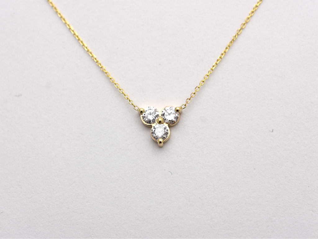 14k yellow gold necklace with a three-stone pendant of round brilliant cut 0.60  carat diamonds  on a white background