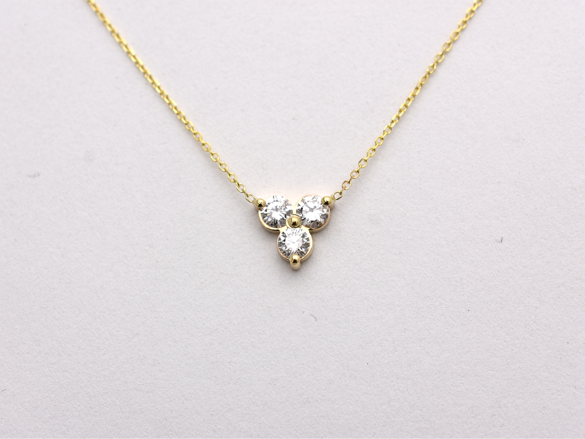 14k yellow gold necklace with a three-stone pendant of round brilliant cut 0.60  carat diamonds  on a white background