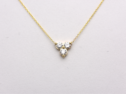 14k yellow gold necklace with a three-stone pendant of round brilliant cut 0.60  carat diamonds  on a white background