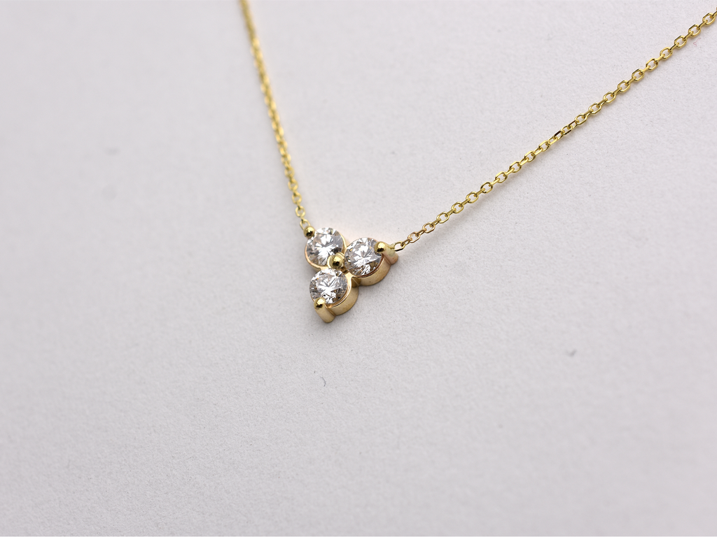 side view 14k yellow gold necklace with a three-stone pendant of round brilliant cut 0.60  carat diamonds  on a white background