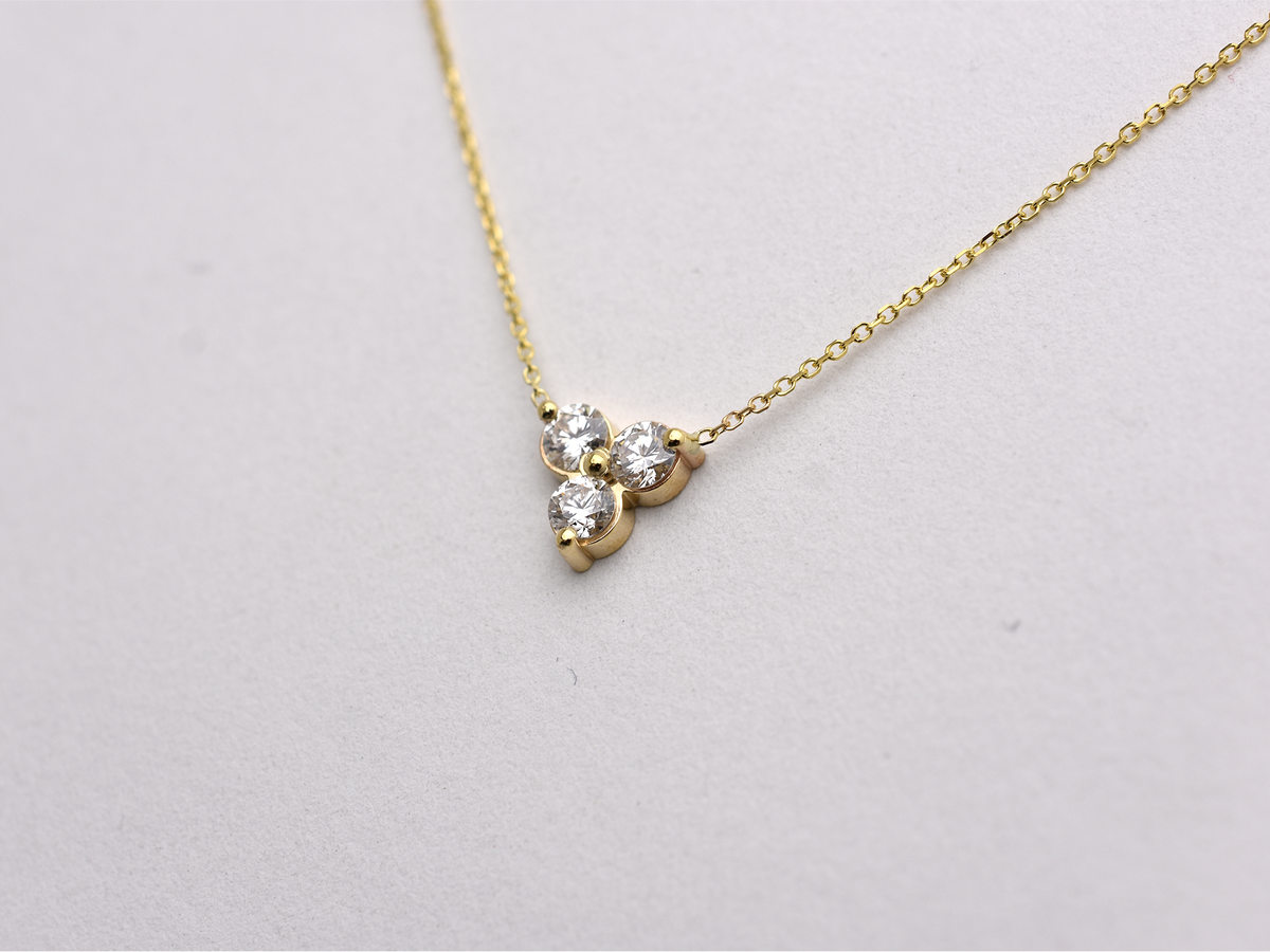 side view 14k yellow gold necklace with a three-stone pendant of round brilliant cut 0.60  carat diamonds  on a white background