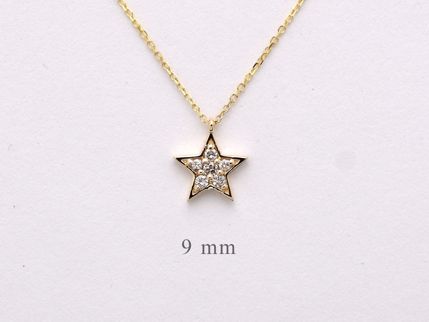 Dainty 14k gold diamond star necklace displayed on a white background.