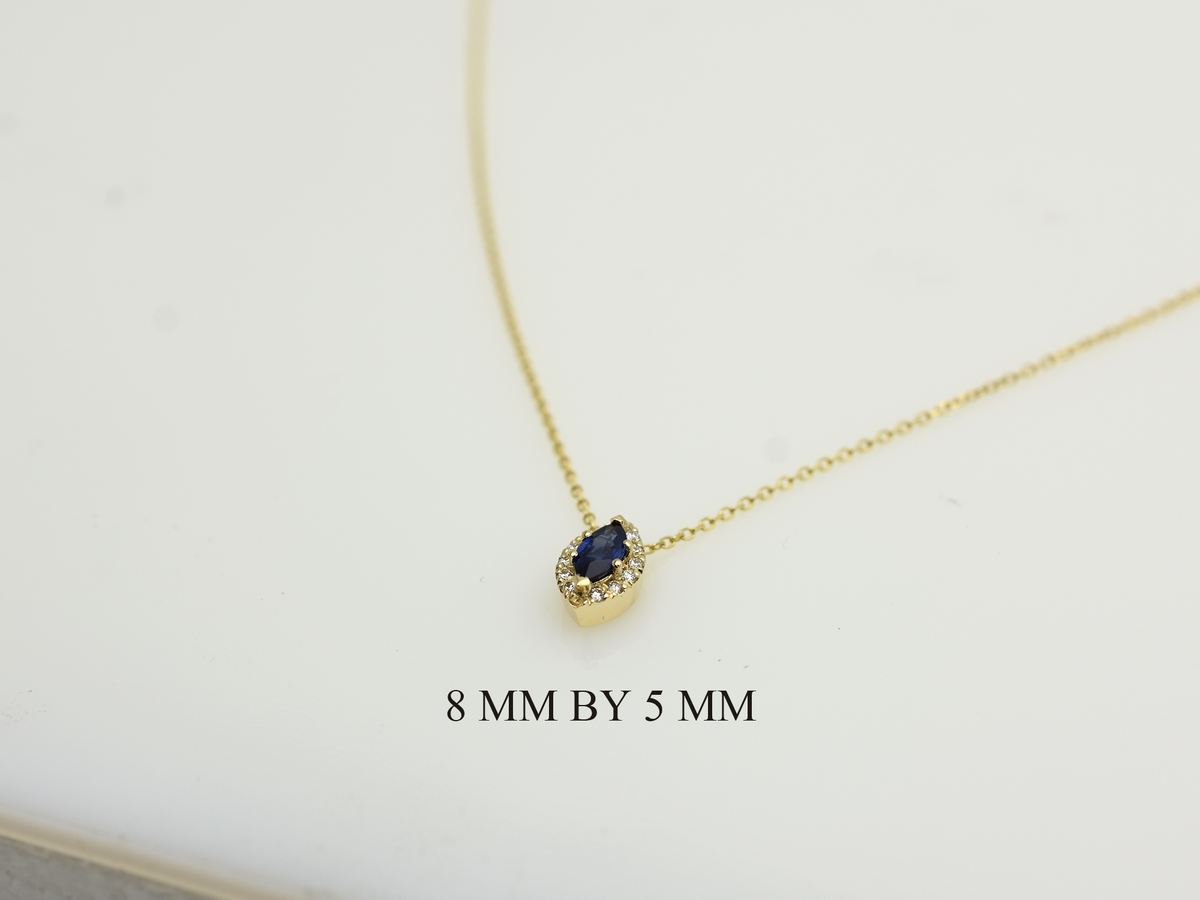  14K gold necklace featuring a marquise-cut sapphire center stone surrounded by a delicate diamond halo displayed on white background