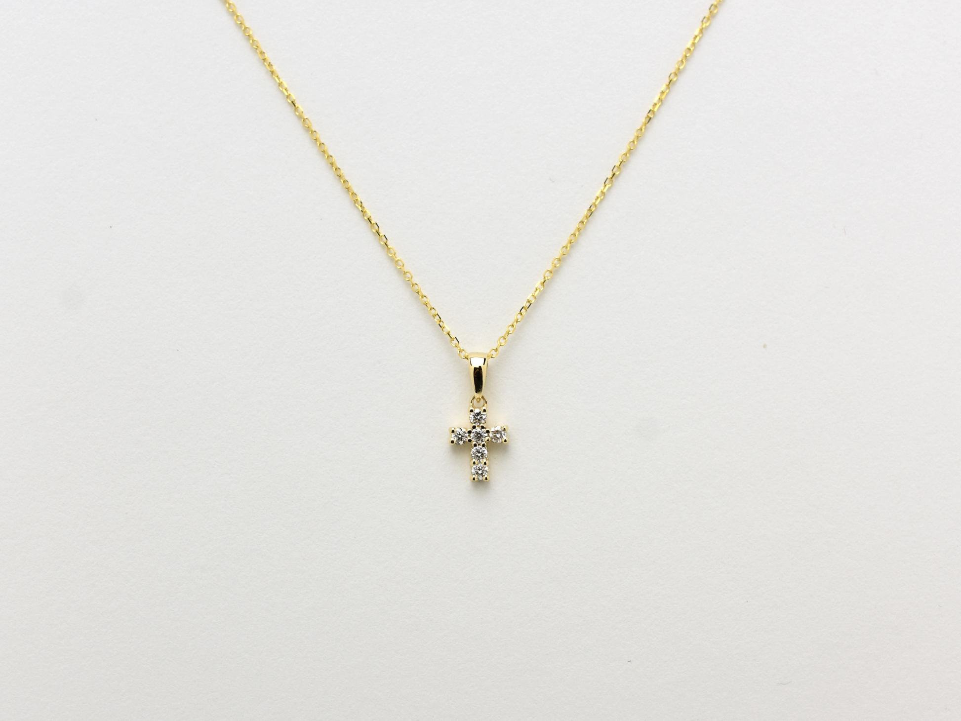14K gold diamond cross pendant on display