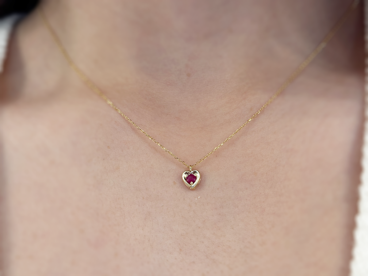14k gold heart shaped necklace minimalistic design . in the center is a 3 mm natural red ruby , the chain is a 0.8mm dainty cable link chain 