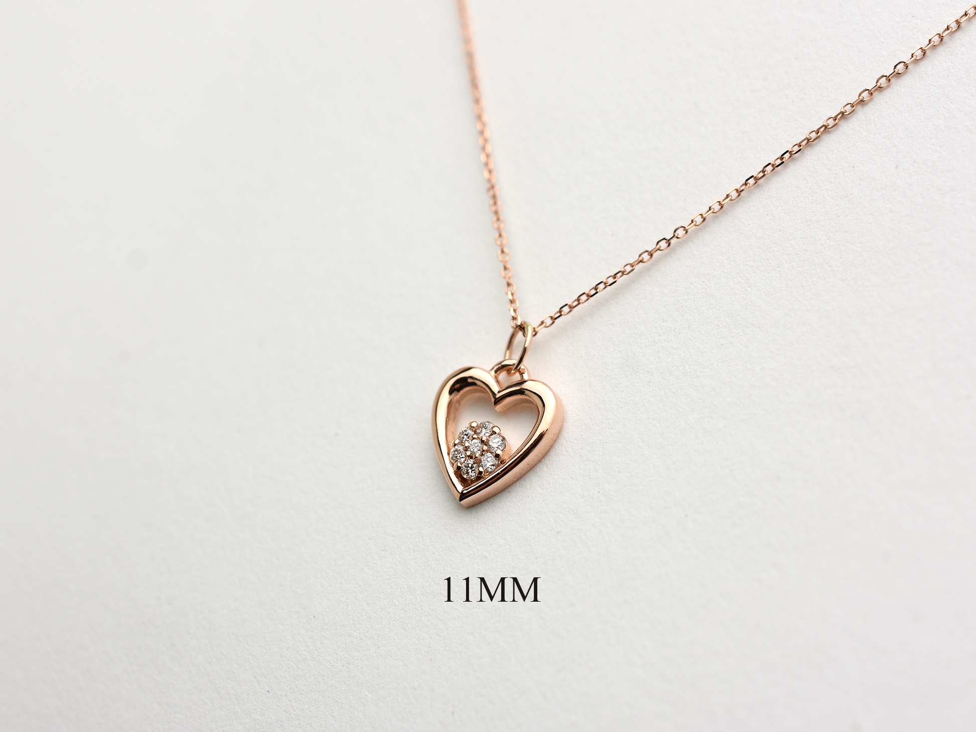 featuring a 14k gold heart necklace with a flower cluster motive 11 mm in dimension . the chain is a 14k sold gold cable link chain with a lobster lock 