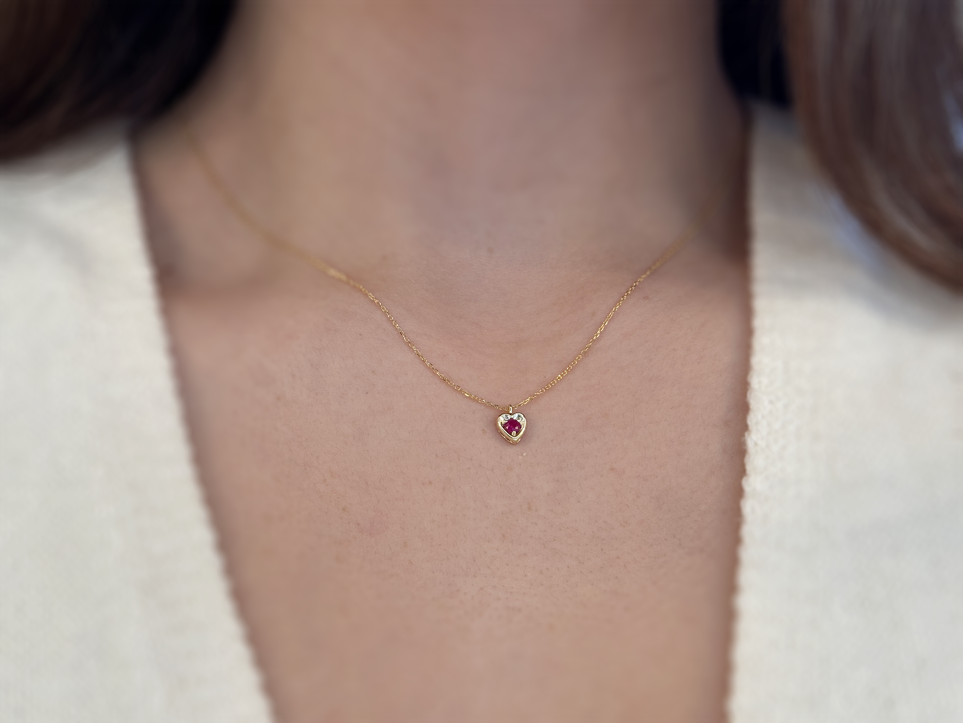 14k gold heart shaped necklace minimalistic design . in the center is a 3 mm natural red ruby , the chain is a 0.8mm dainty cable link chain displayed on a white background