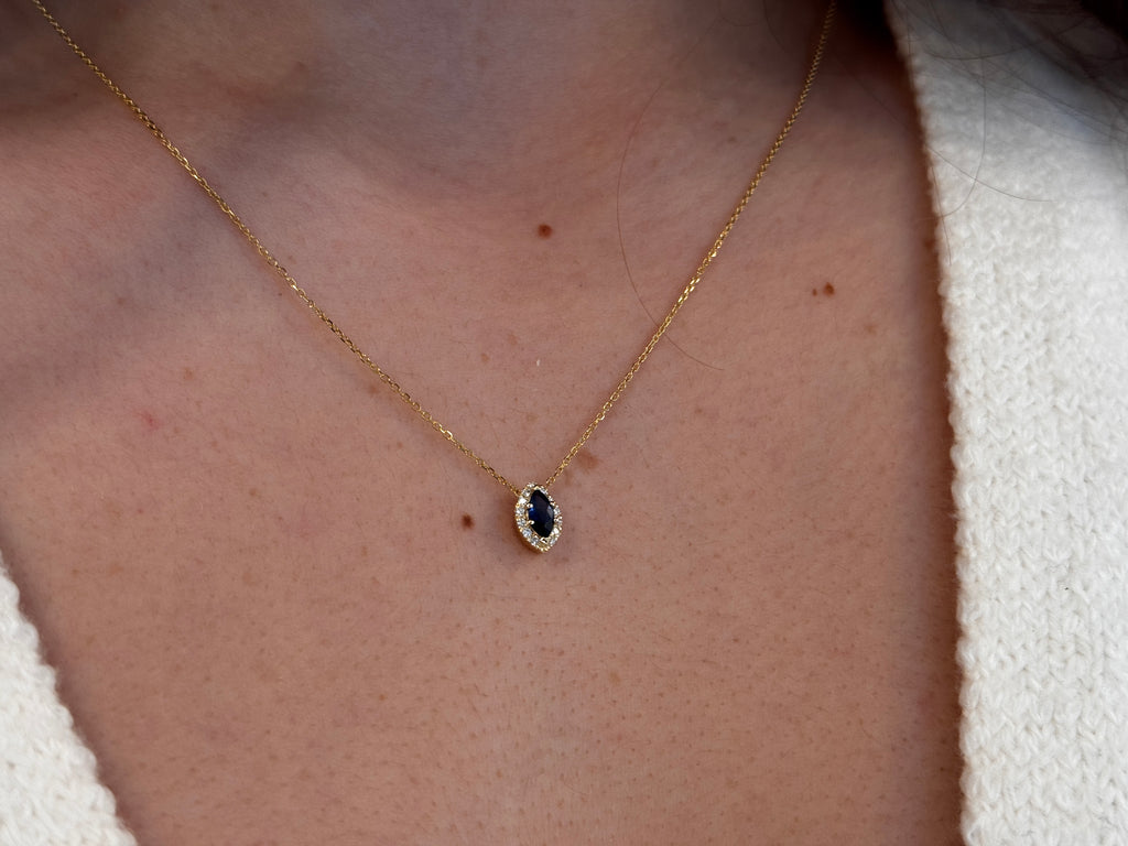  14K gold necklace featuring a marquise-cut sapphire center stone surrounded by a delicate diamond halo displayed on a model