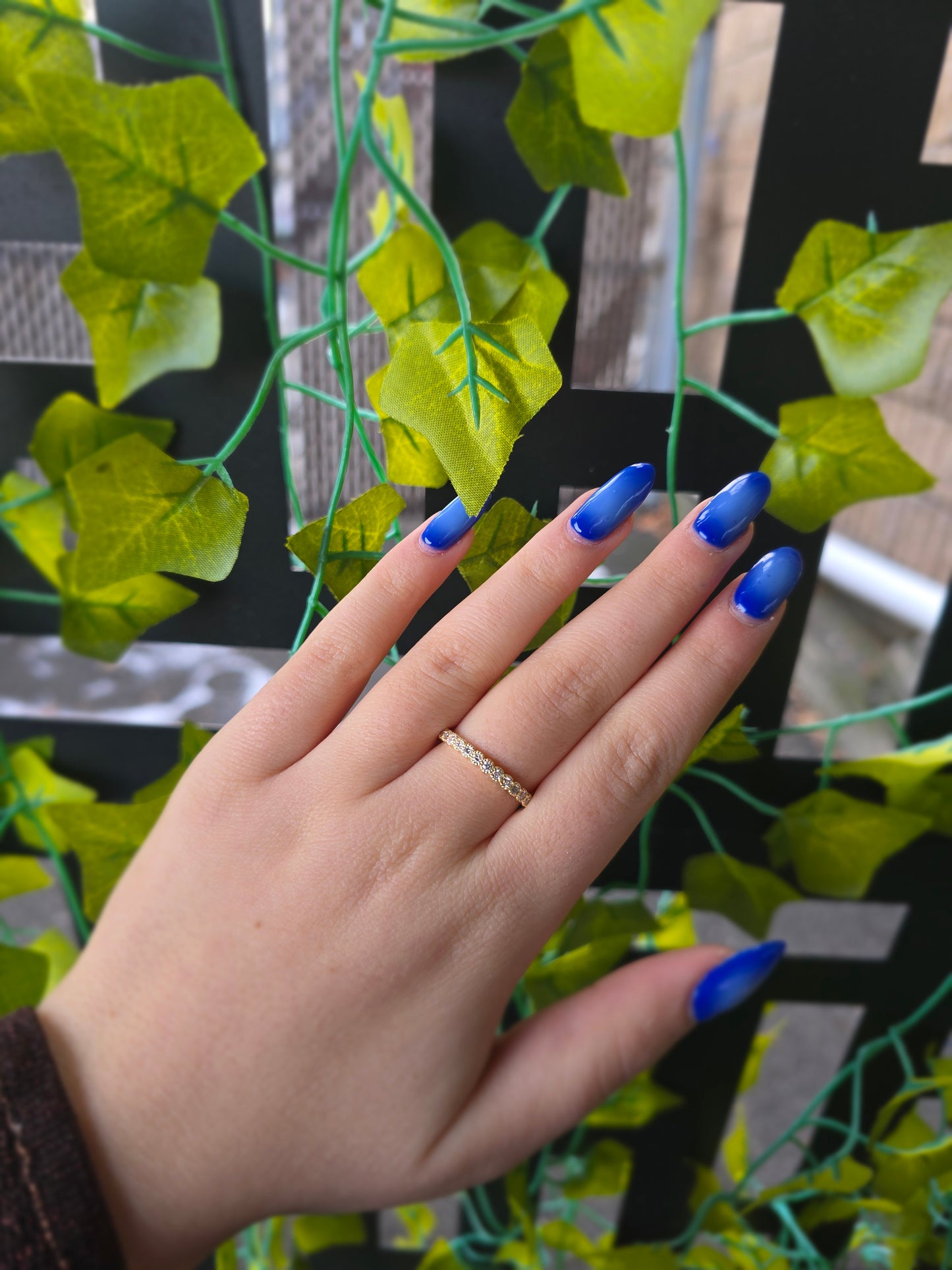14k yellow gold dainty wedding band featuring a row of round diamonds. Each diamond is set in a scalloped bezel with fine milgrain beaded edges. The ring is shown on a reflective white surface, highlighting the warm gold tones and sparkling stones.