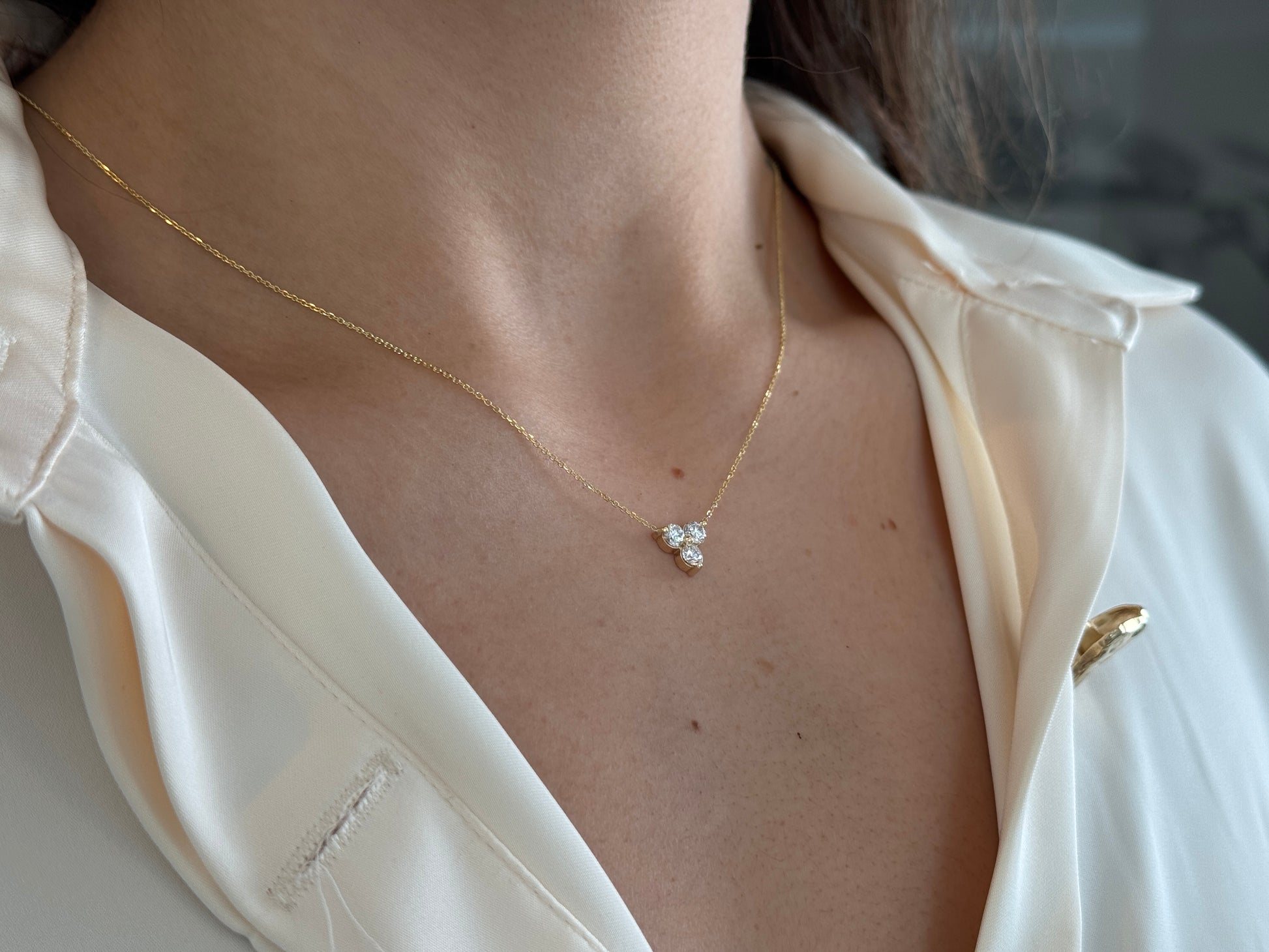 14k yellow gold necklace with a three-stone pendant of round brilliant cut diamonds  on a model