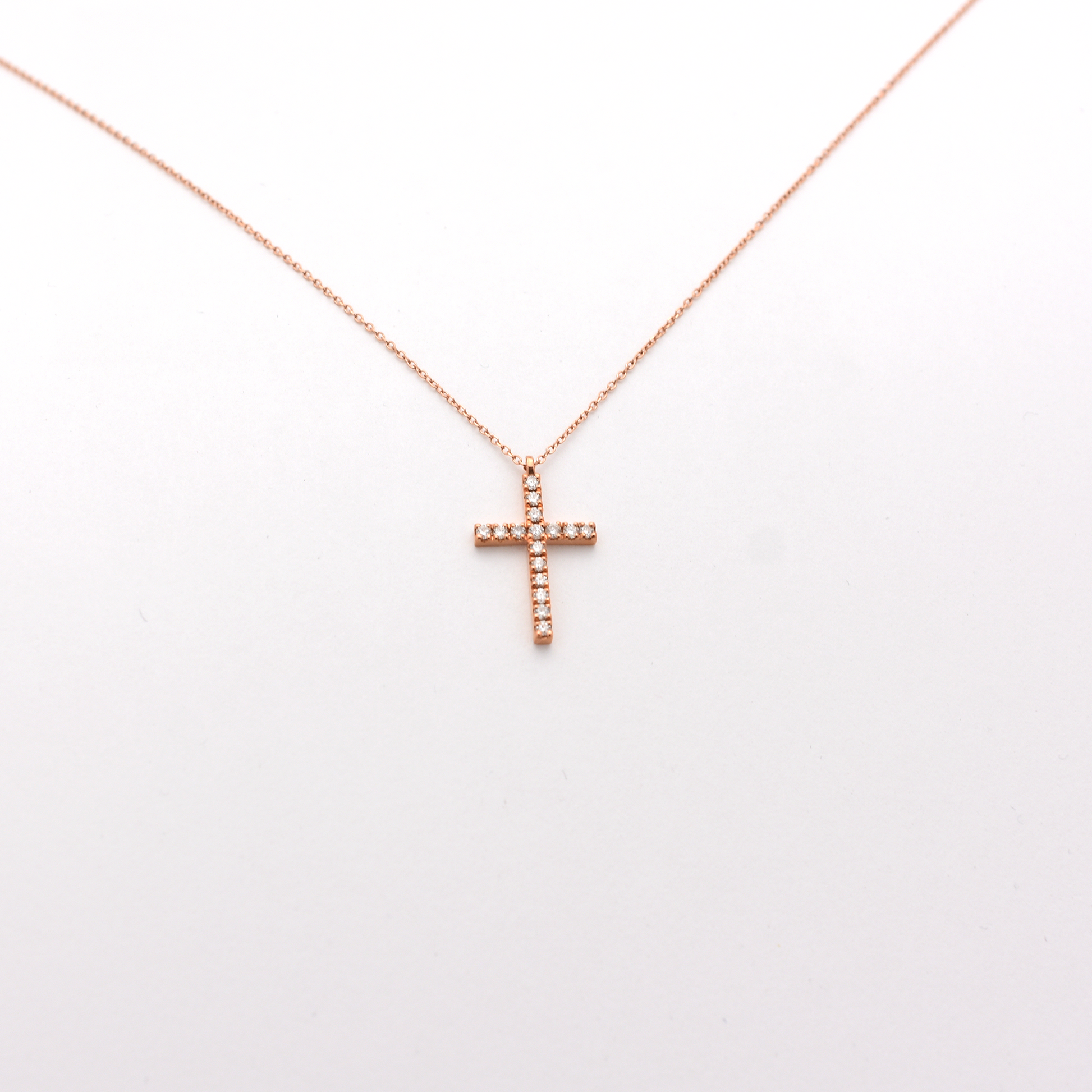 A dainty diamond cross necklace with a 14k rose gold chain.