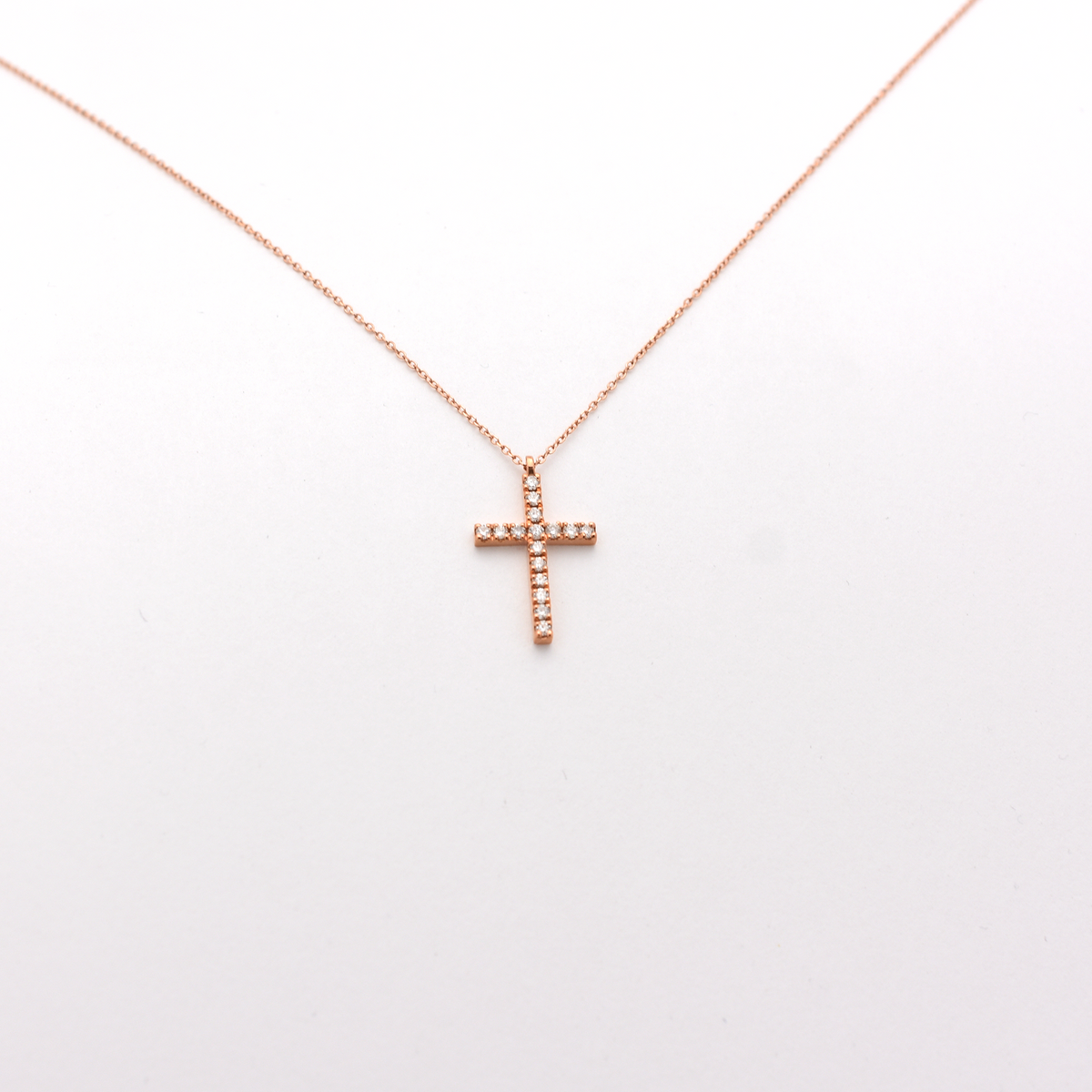 A dainty diamond cross necklace with a 14k rose gold chain.