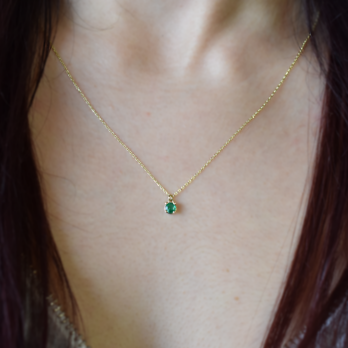 A 14k gold necklace with a single emerald stone pendant. 4 PRONG SETTING ON THE BODY
