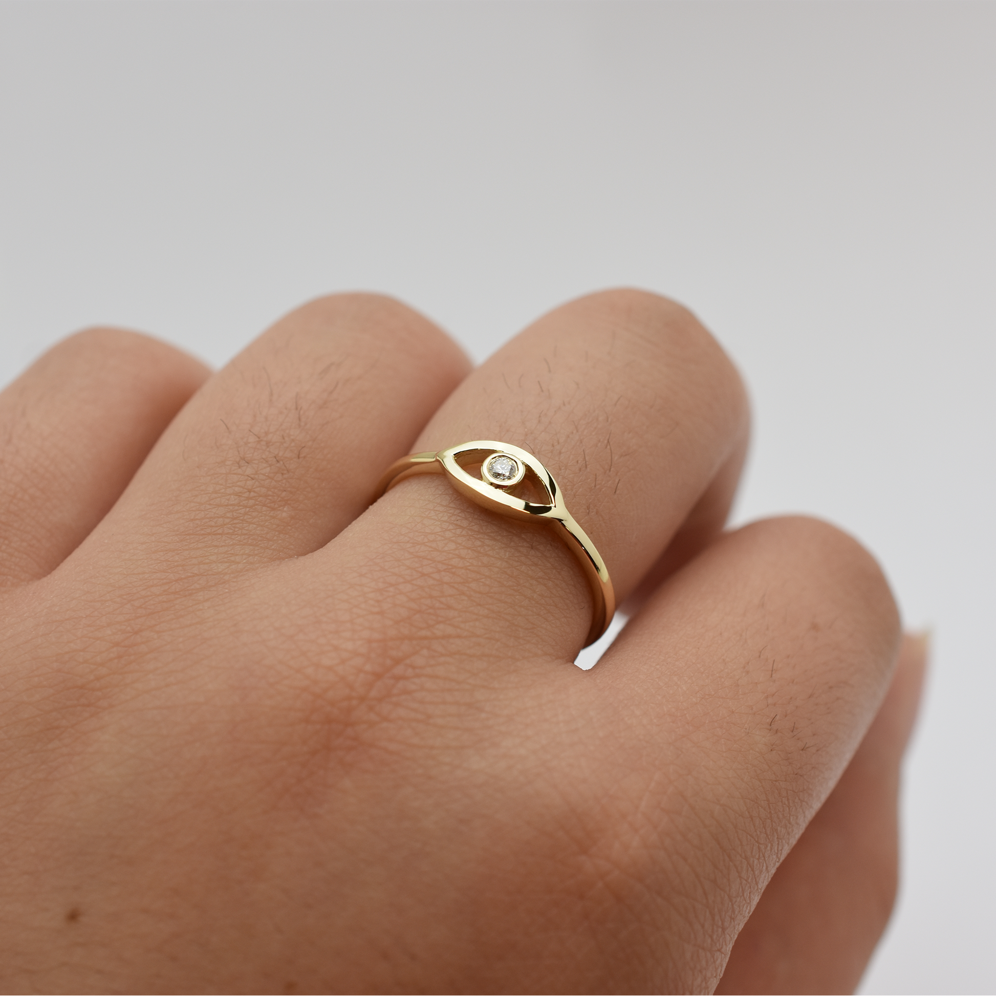 14k gold evil eye ring with a diamond on a finger