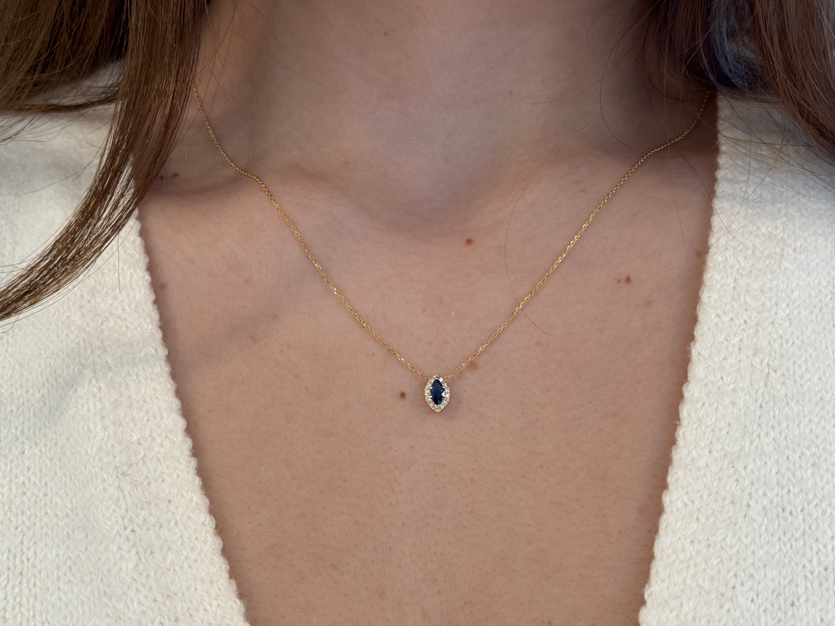  14K gold necklace featuring a marquise-cut sapphire center stone surrounded by a delicate diamond halo displayed on white background