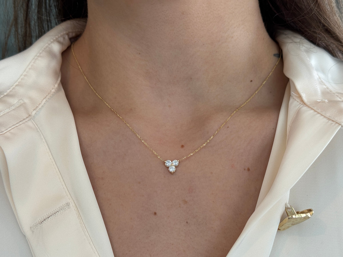 14k yellow gold necklace with a three-stone pendant of round brilliant cut diamonds  on a model