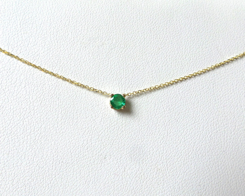 14k gold natural round shaped emerald set in a 4 prong setting with a delicate chain floating 