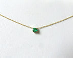 14k gold natural round shaped emerald set in a 4 prong setting with a delicate chain floating 