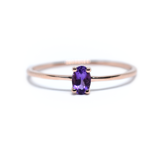 A 14K gold oval amethyst ring with a thin band, featuring a single purple stone on a white background.