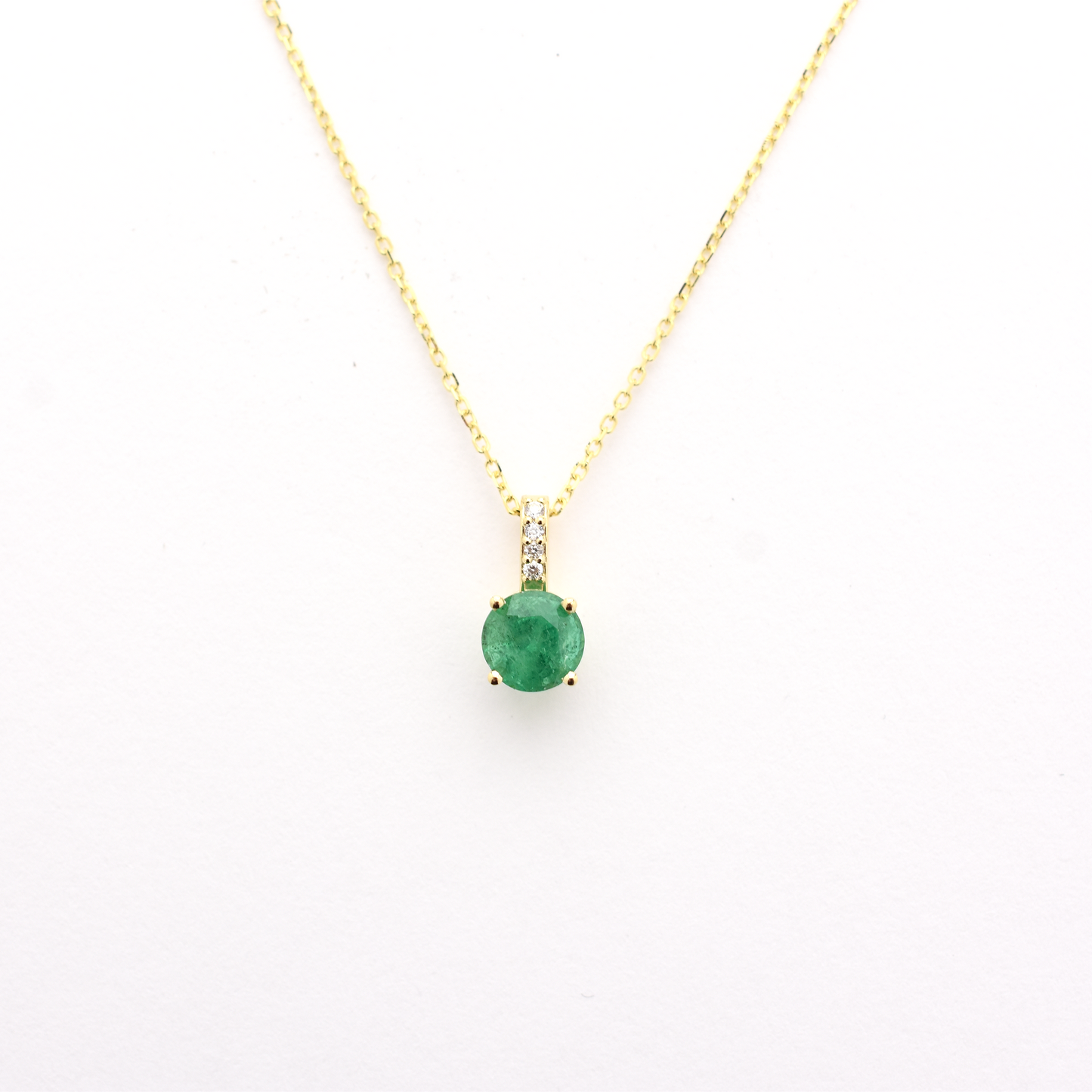 A 14k gold emerald diamond necklace with a single emerald pendant on a chain.
