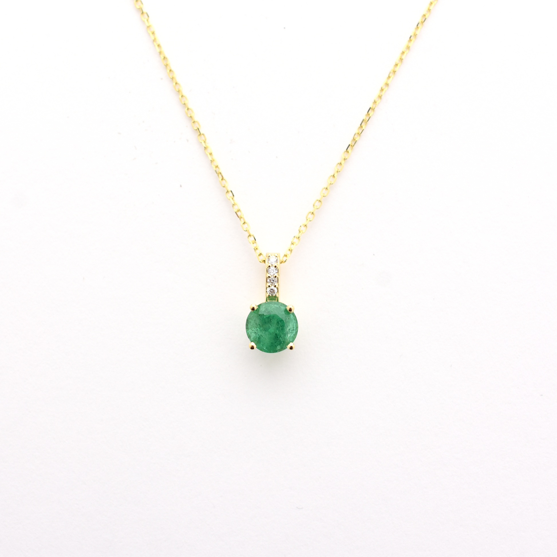 A 14k gold emerald diamond necklace with a single emerald pendant on a chain.