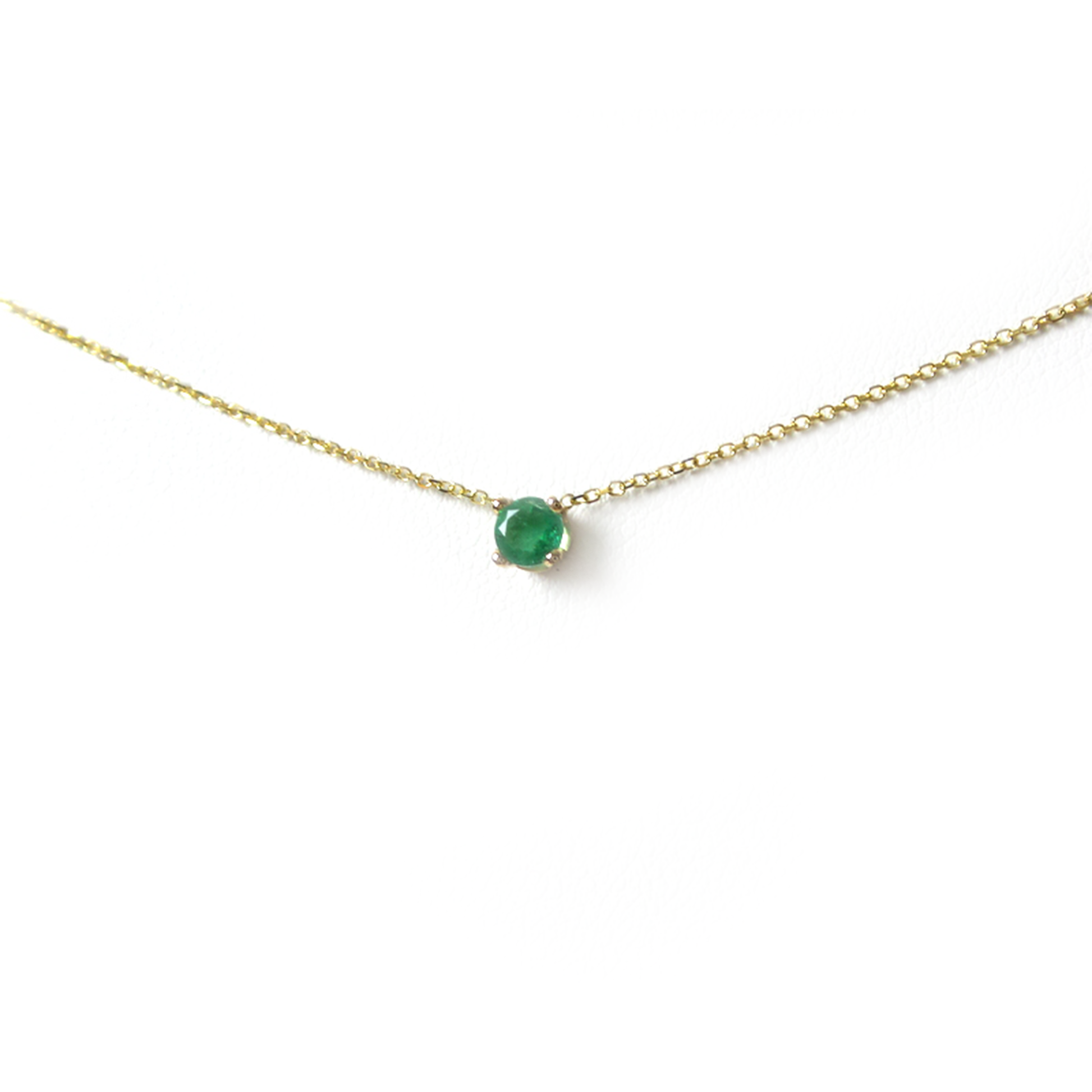 14k gold natural round shaped emerald set in a 4 prong setting with a delicate chain floating 