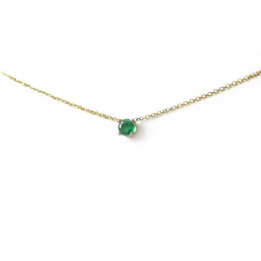 14k gold natural round shaped emerald set in a 4 prong setting with a delicate chain floating 