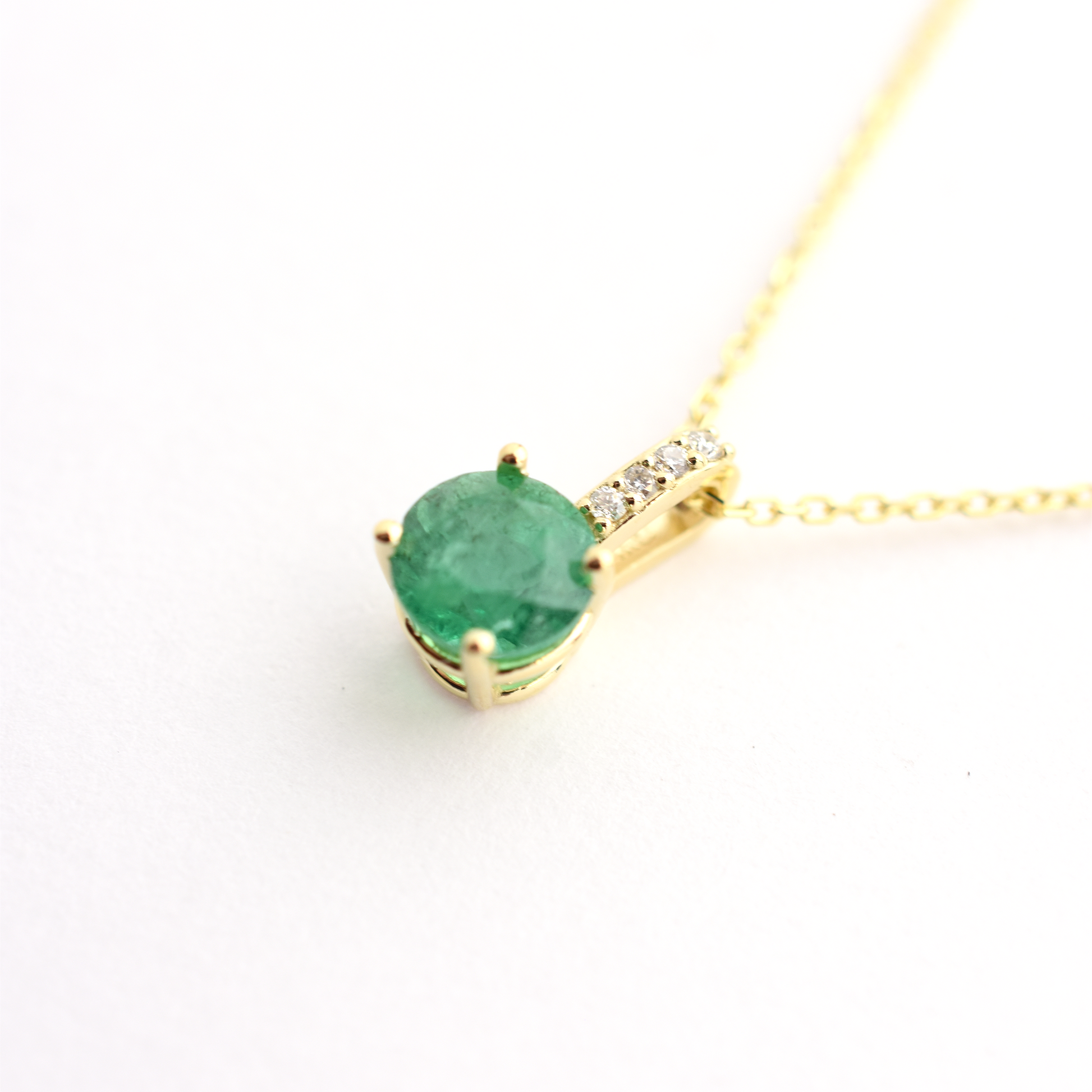 14k gold diamond and emerald solitaire necklace white background close up