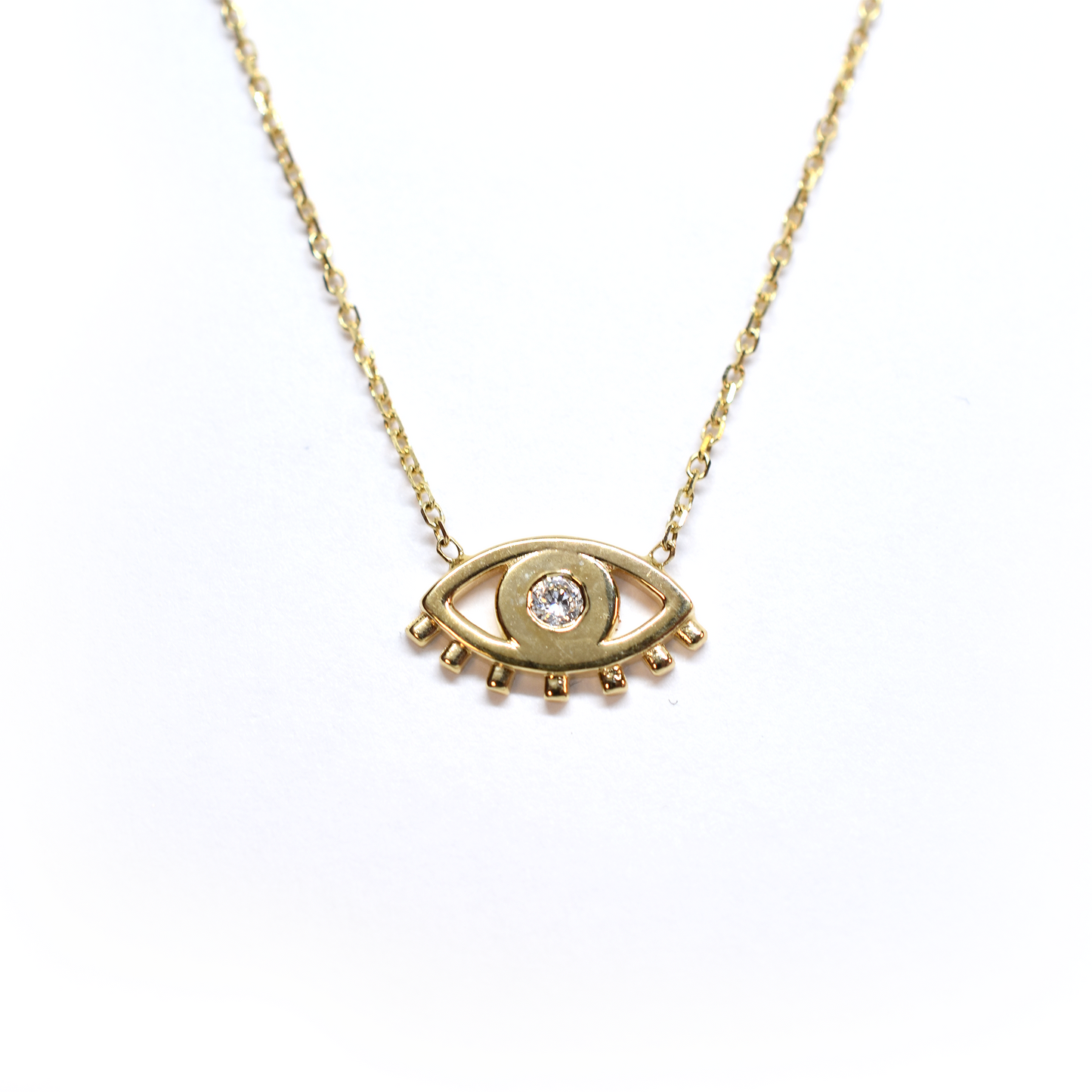A 14k gold necklace featuring a single diamond-studded pendant, resembling an evil eye, on a white background.