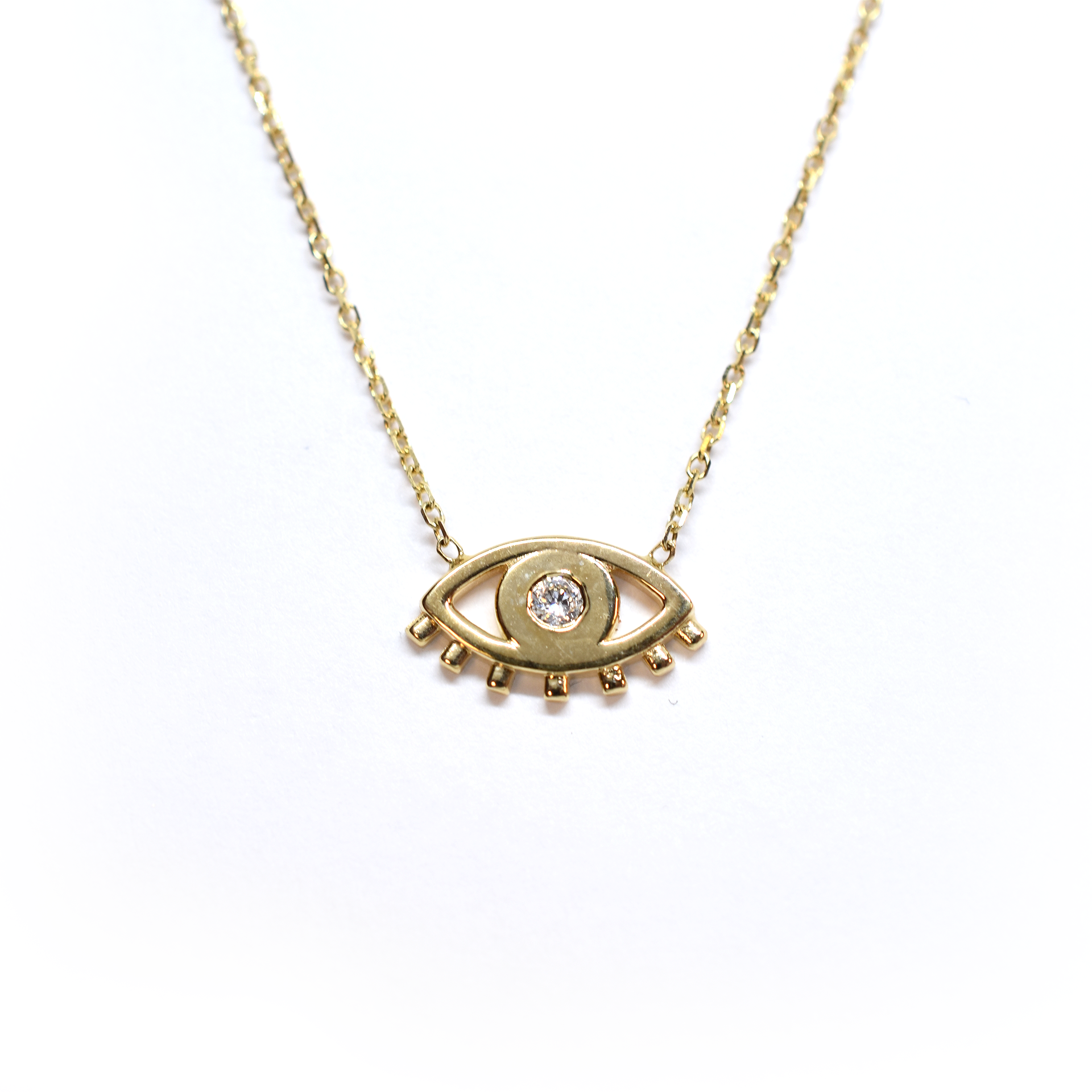 A 14k gold necklace featuring a single diamond-studded pendant, resembling an evil eye, on a white background.