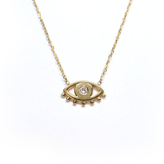 A 14k gold necklace featuring a single diamond-studded pendant, resembling an evil eye, on a white background.
